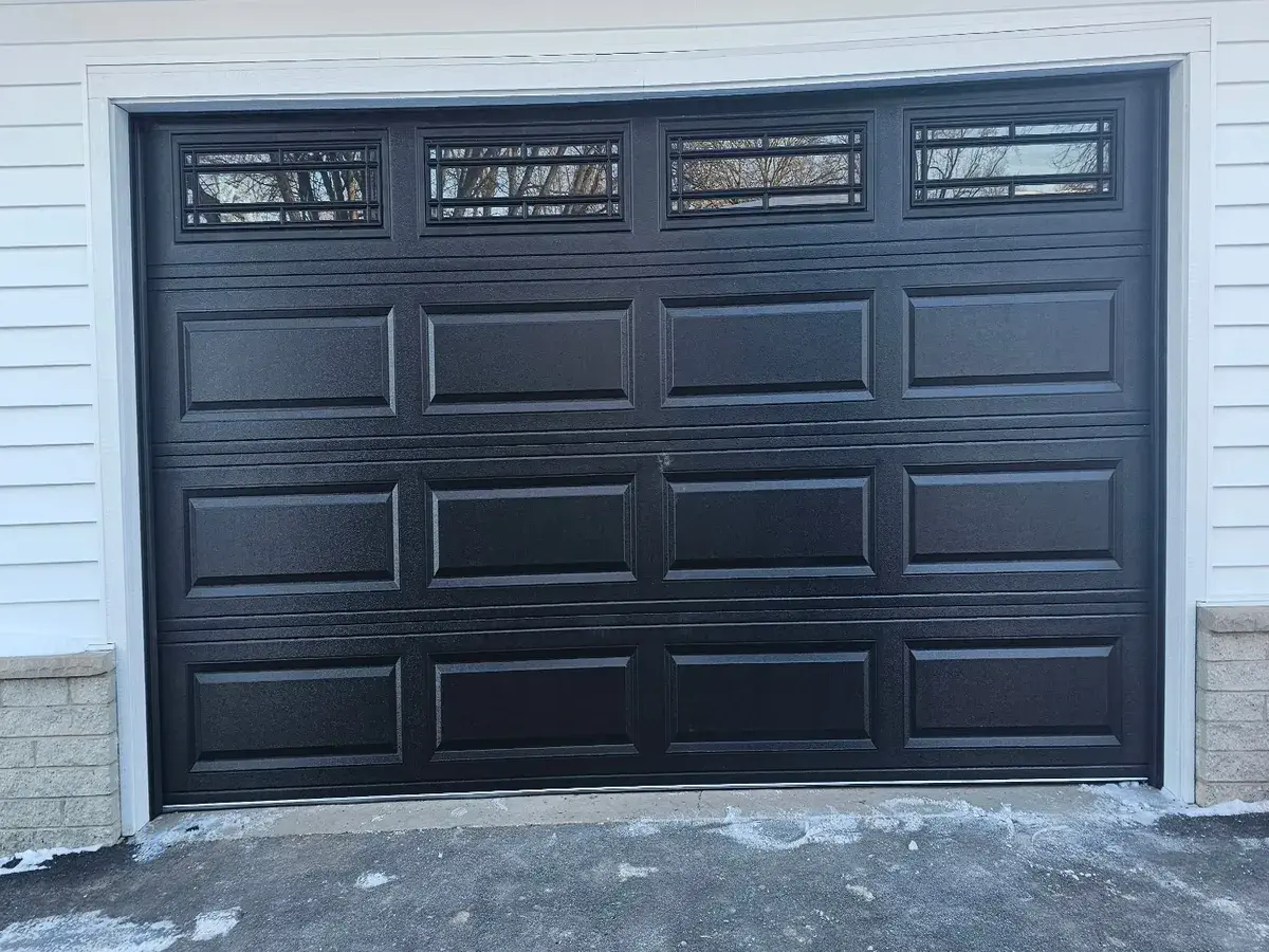 Black raised panel garage door with a row of window inserts across the top