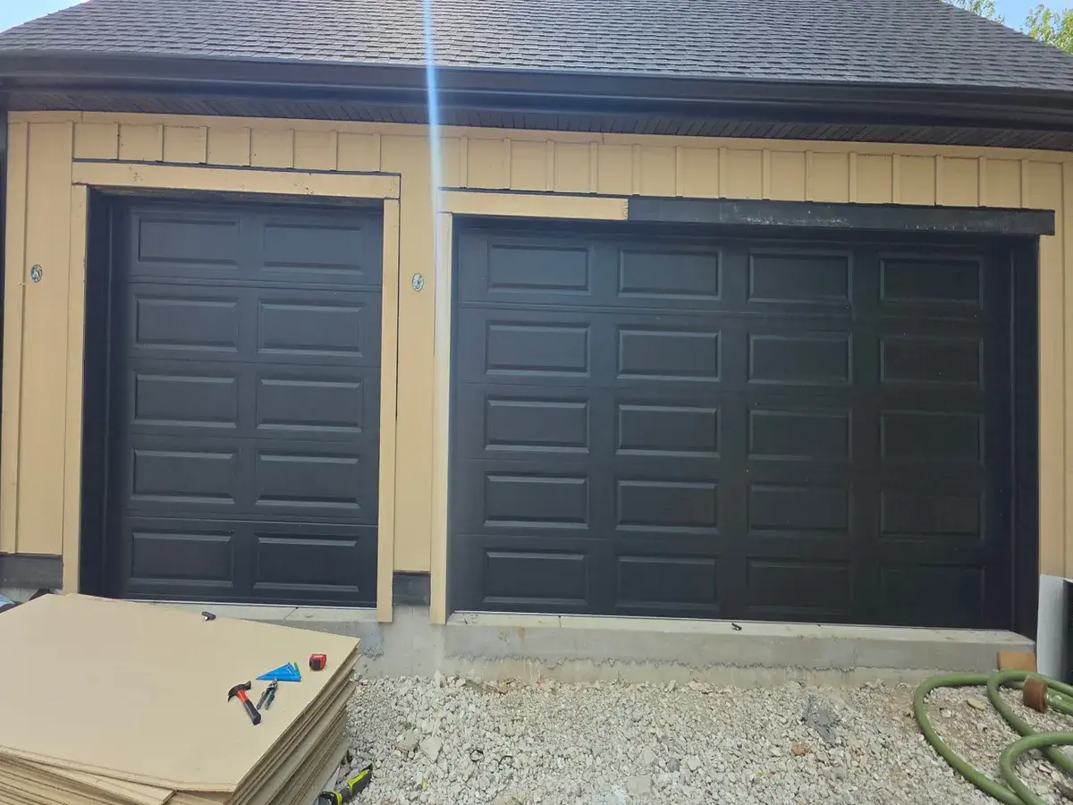 Two black garage doors installed on a new construction garage