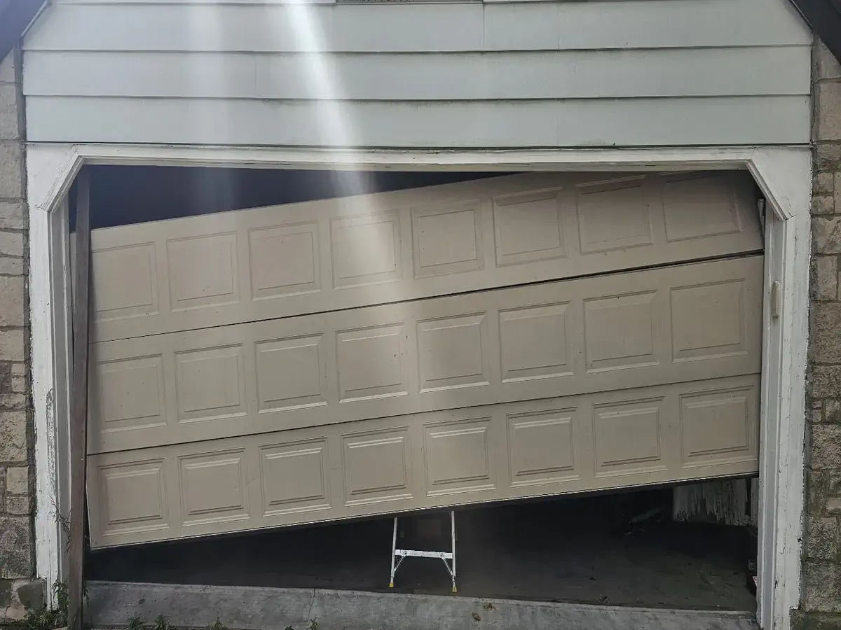 Damaged beige garage door before it was replaced