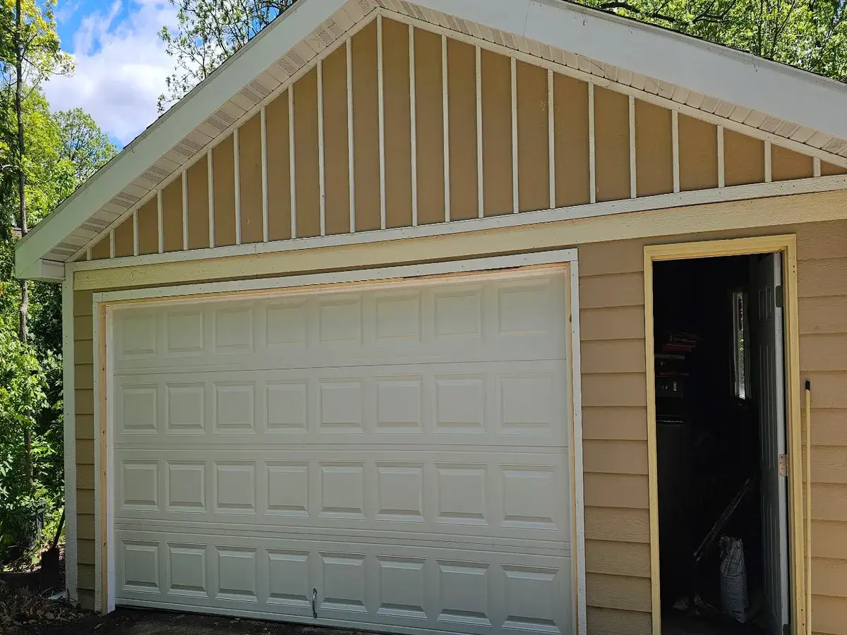 Cream raised panel double garage door on a tan board and batten garage