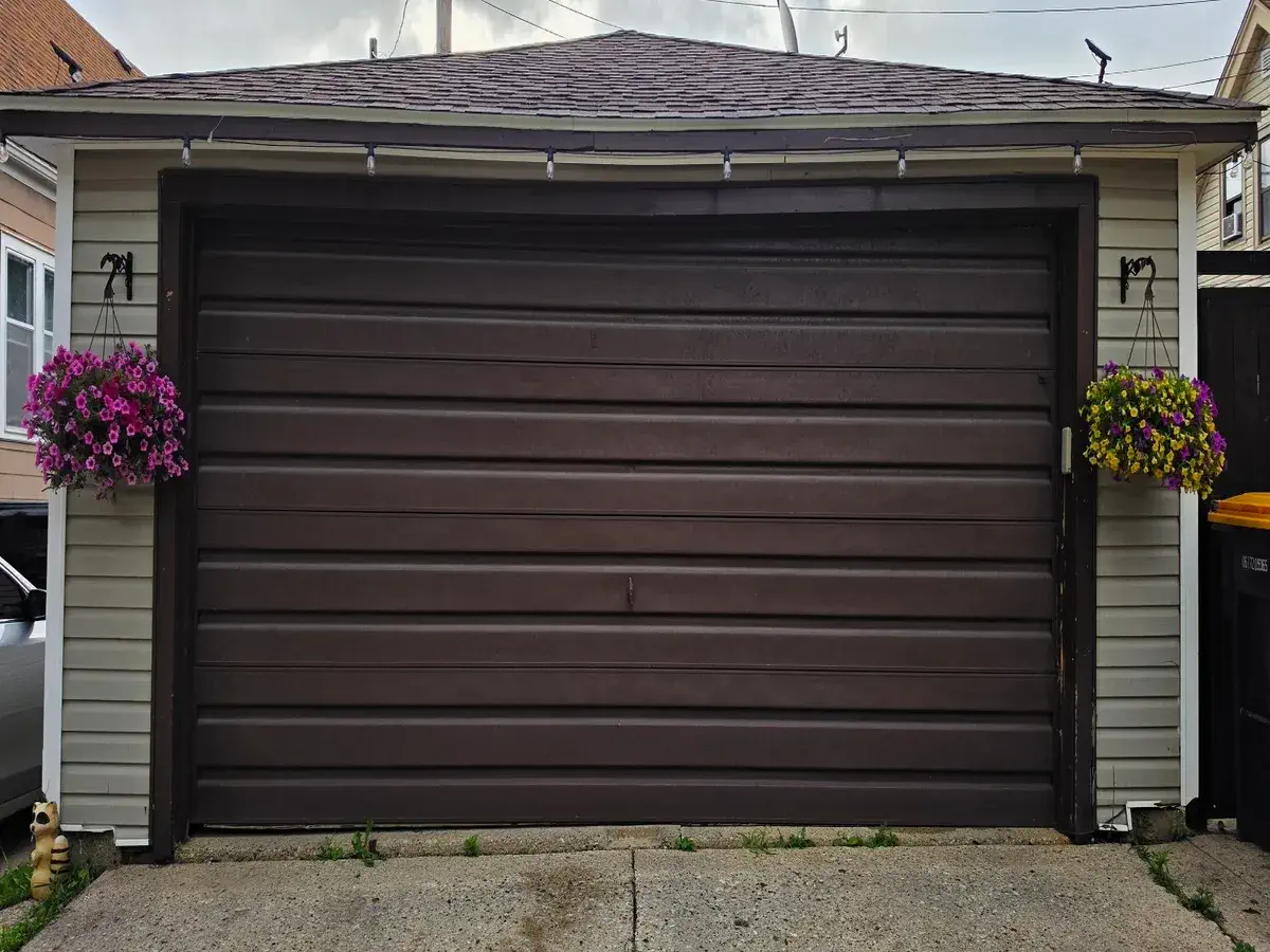 Dark brown long panel garage door on a cream sided garage in Southeast Wisconsin