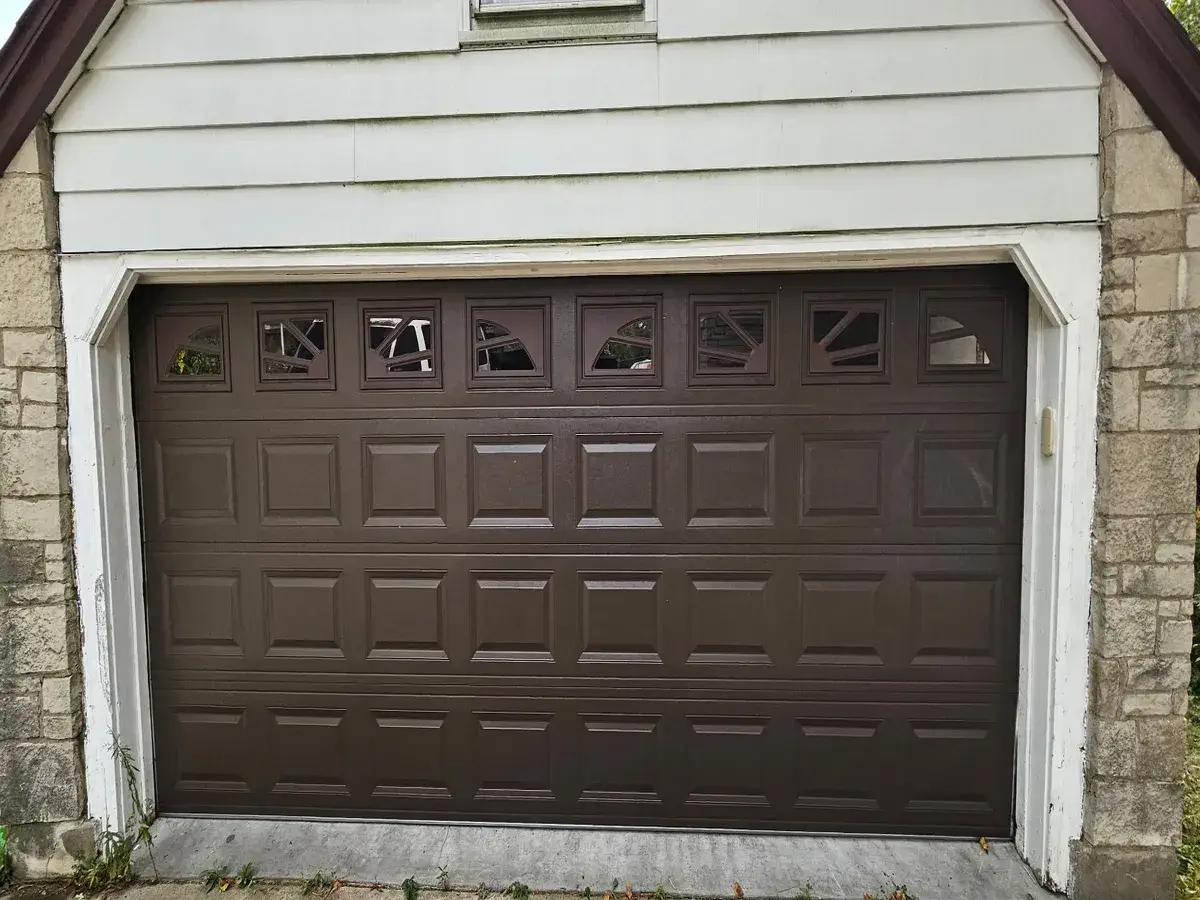 Brown garage door with a row of windows on a white sided two car garage