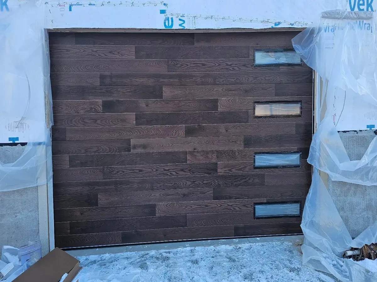 Dark brown wood plank garage door being installed on a new build