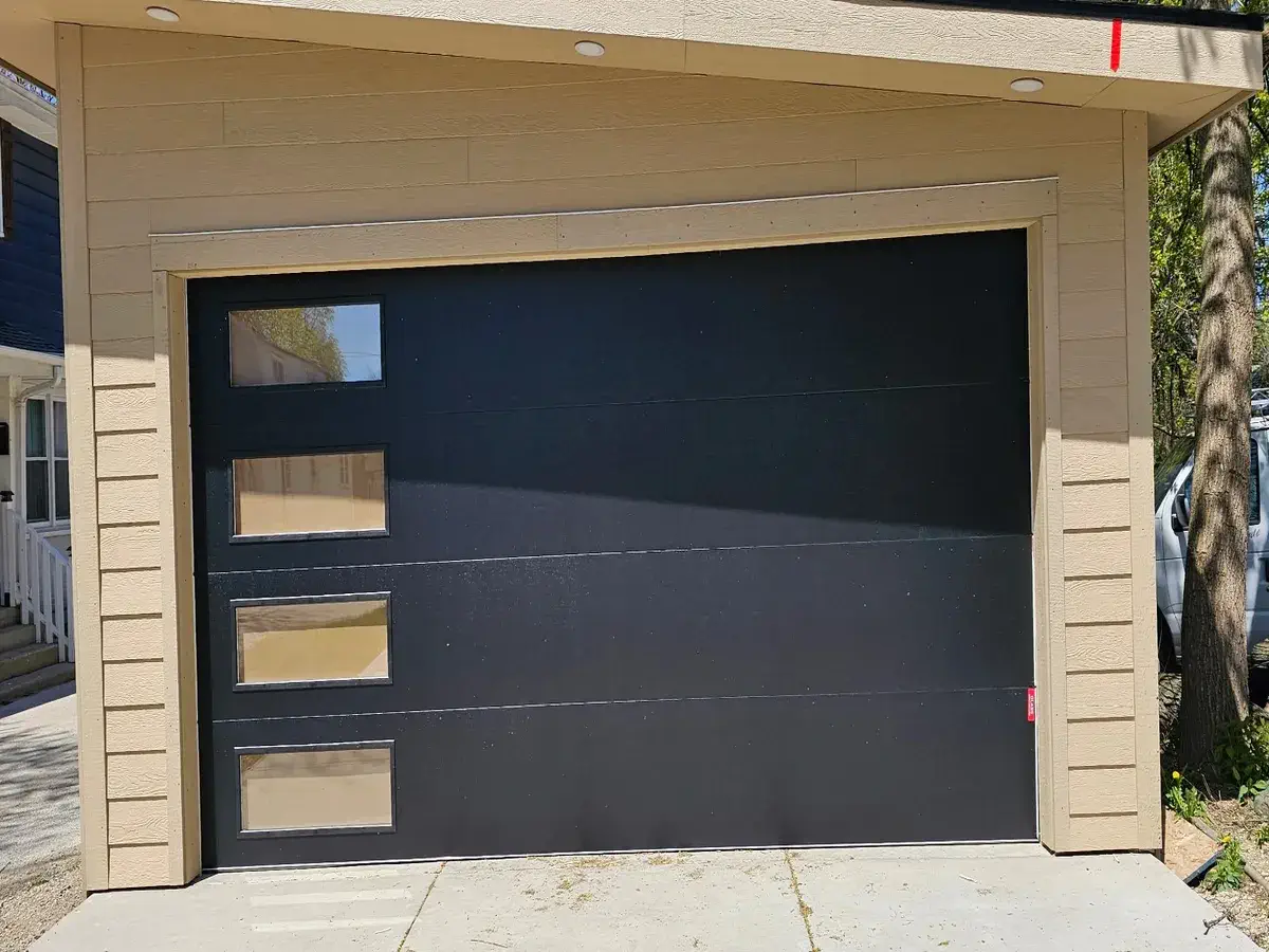 Modern flush black garage door with a vertical row of windows