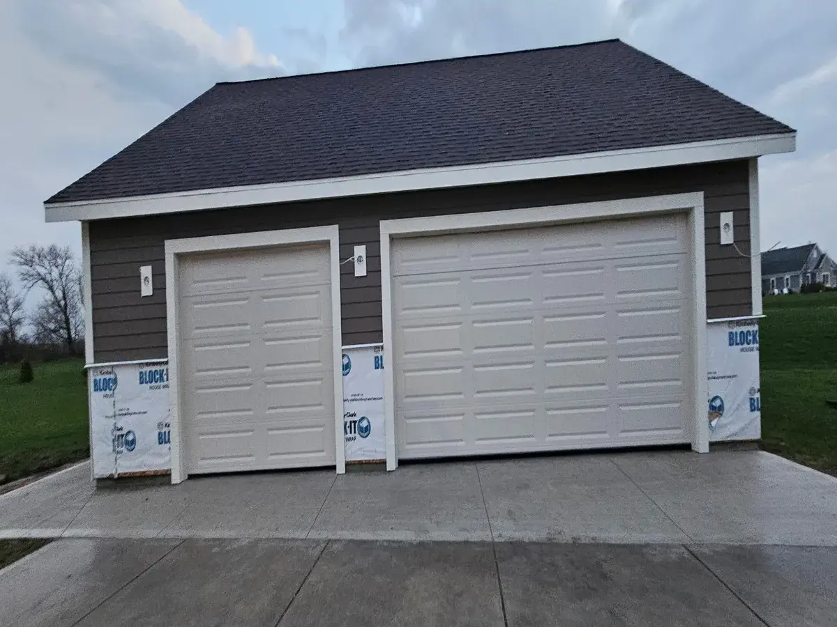 Two white garage doors installed on a new construction garage